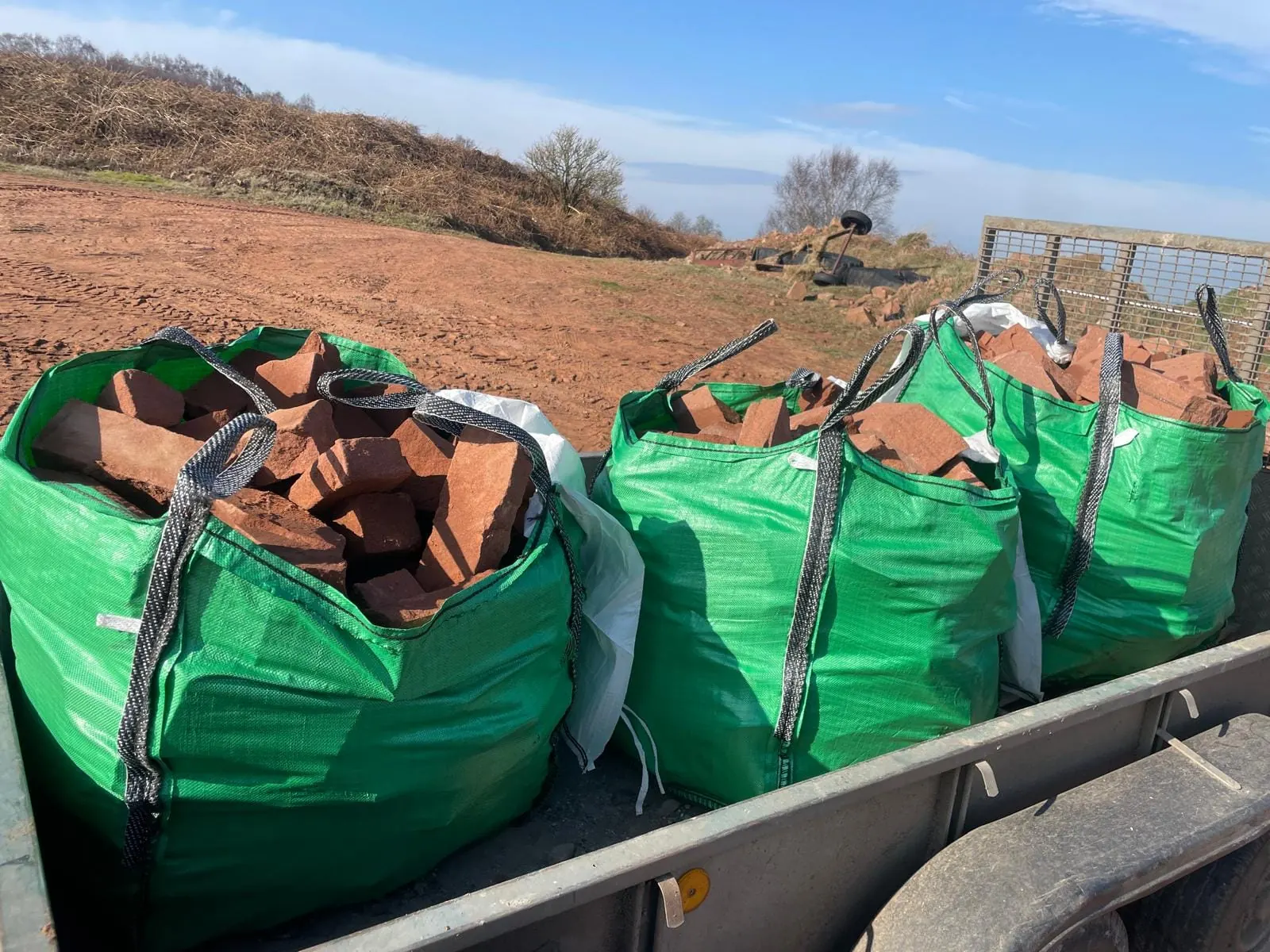 Green bulk bags of red sandstone loaded on a trailer at the quarry