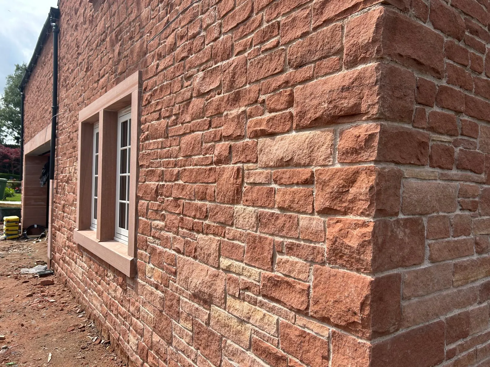 Long elevation of a red sandstone house with paired windows