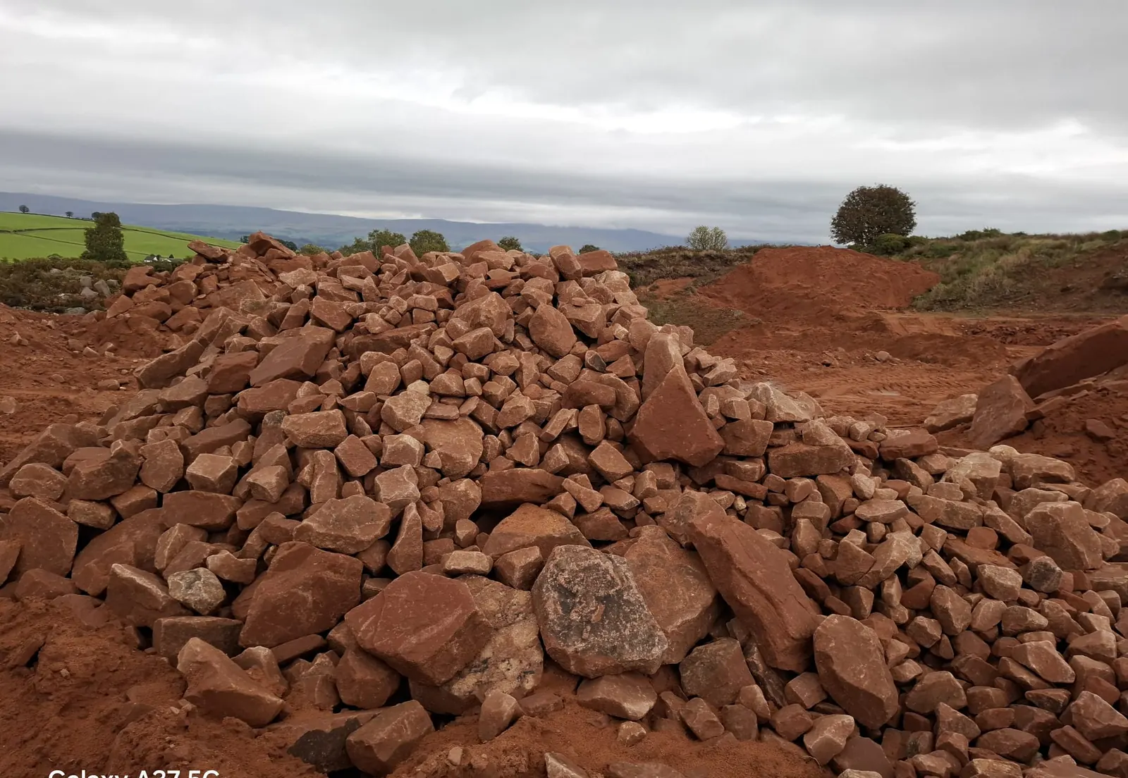 A stockpile of red sandstone at the quarry with the Pennines on the horizon